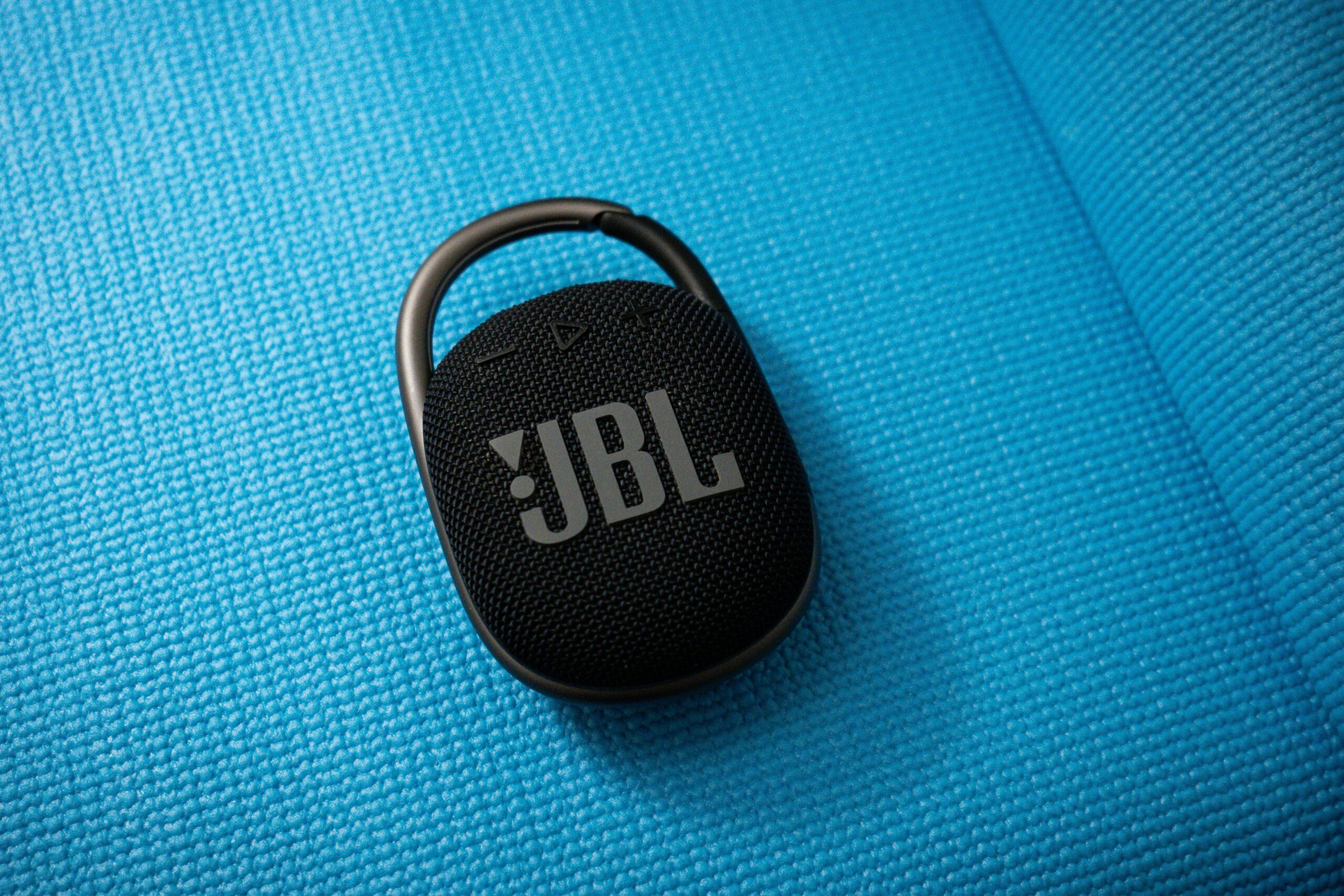 pexels photo 18589085 18589085 Black JBL portable wireless speaker with carabiner on textured blue background. Ideal for travel and outdoor use.